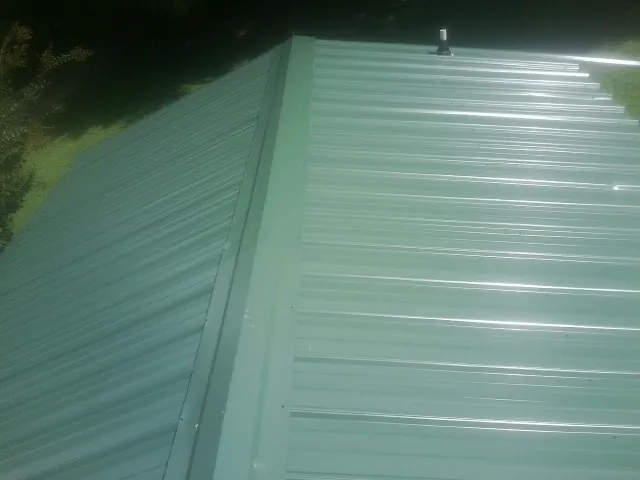 New green metal panels meeting at the ridge of a roof — Flat Roof Repair work by our crew in Table Rock