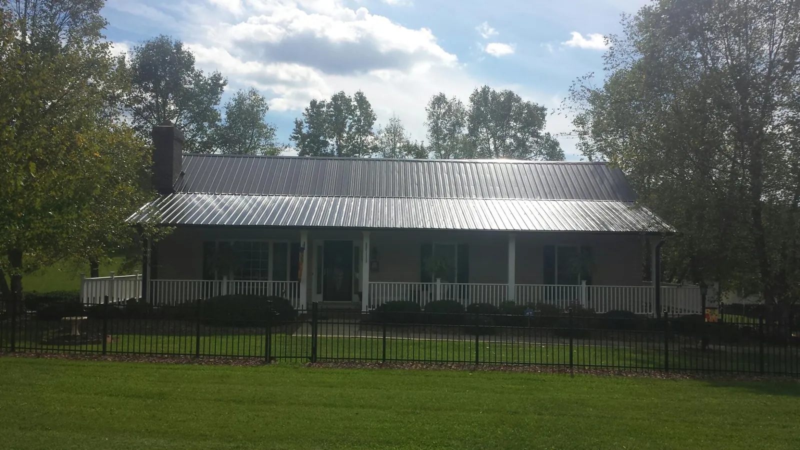 Gray metal roof on a brick ranch with a full width front porch — Gutter Guard Installation work by our crew in Table Rock