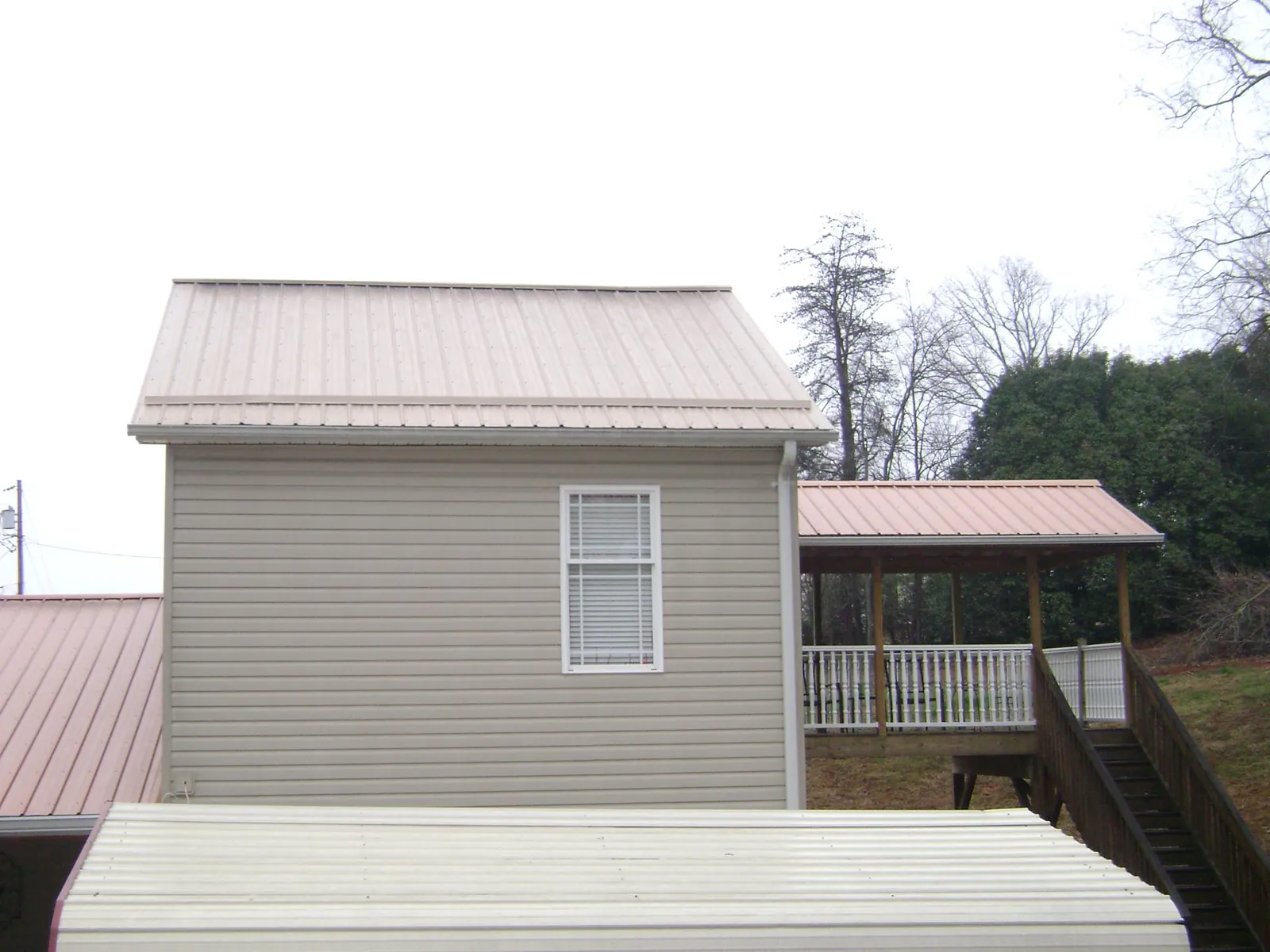 Tan metal roofs on a two story addition and attached porch, from a Roof Replacement job in Table Rock